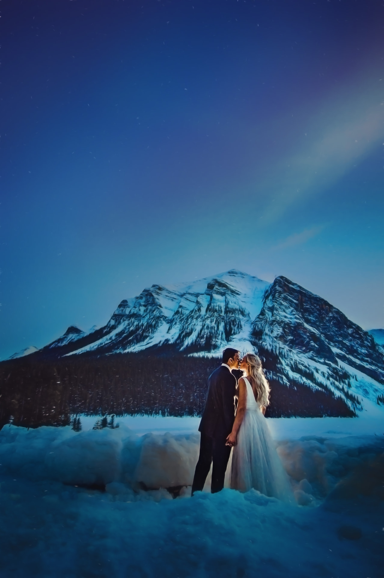 Couple kissing under a starlit winter sky in front of Mount Fairview at Lake Louise