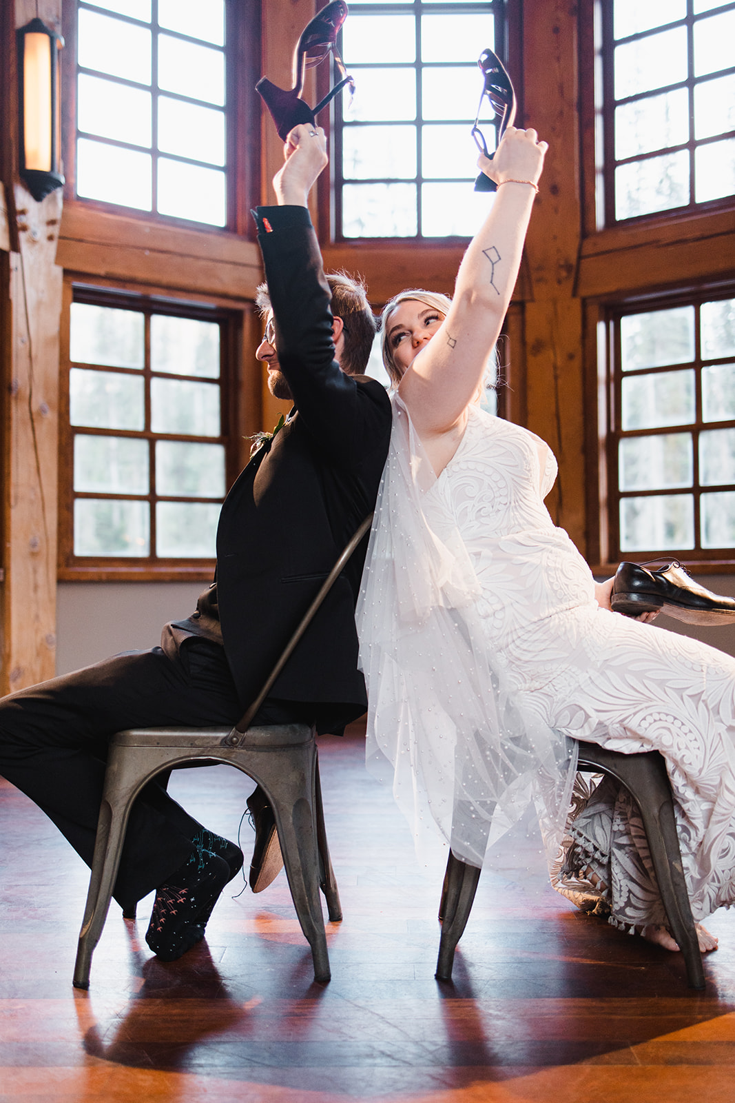 Bride and groom laughing through the shoe game in a timber-framed Rockies lodge