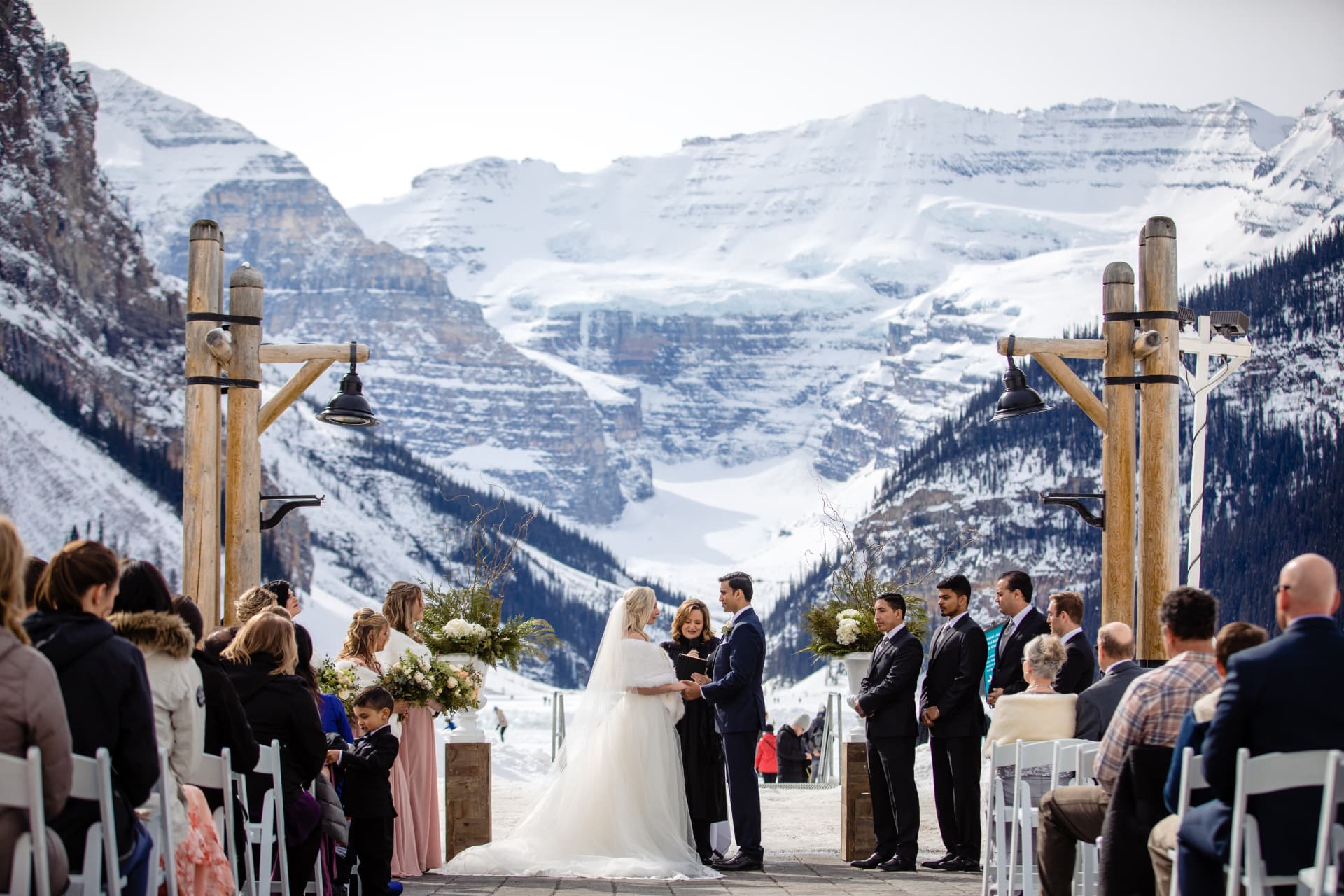 Winter ceremony on the shore of a frozen Lake Louise with guests bundled in fur wraps